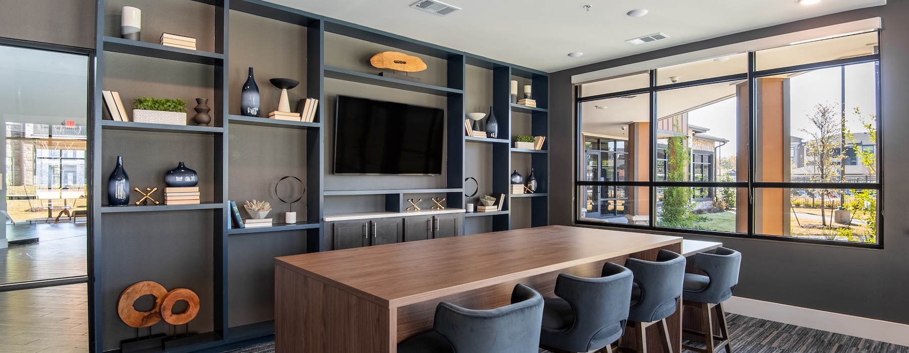 a clubhouse room with a tv and a large tale with chairs