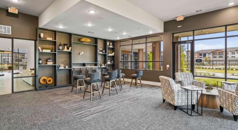 a room with a table chairs and shelves and large windows