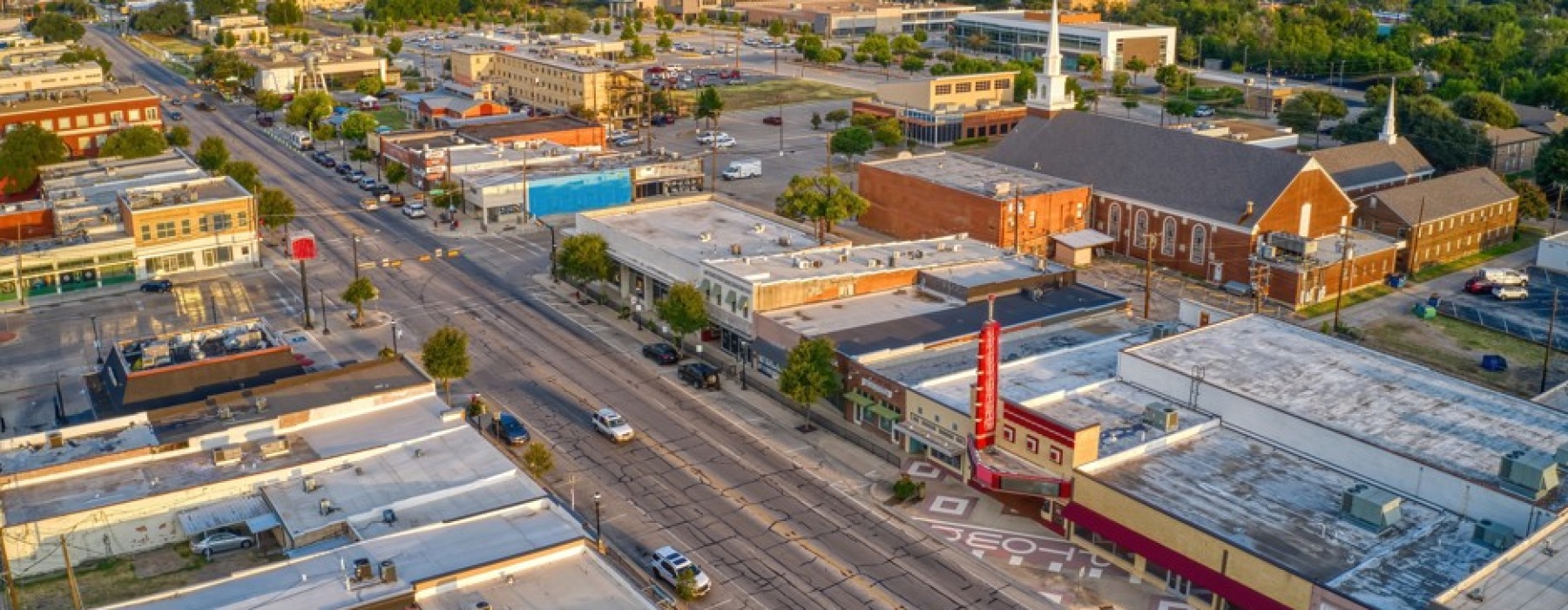Aerial view of Main Street in downtown Grand Prairie, Texas, showing local businesses and historic architecture during sunset.