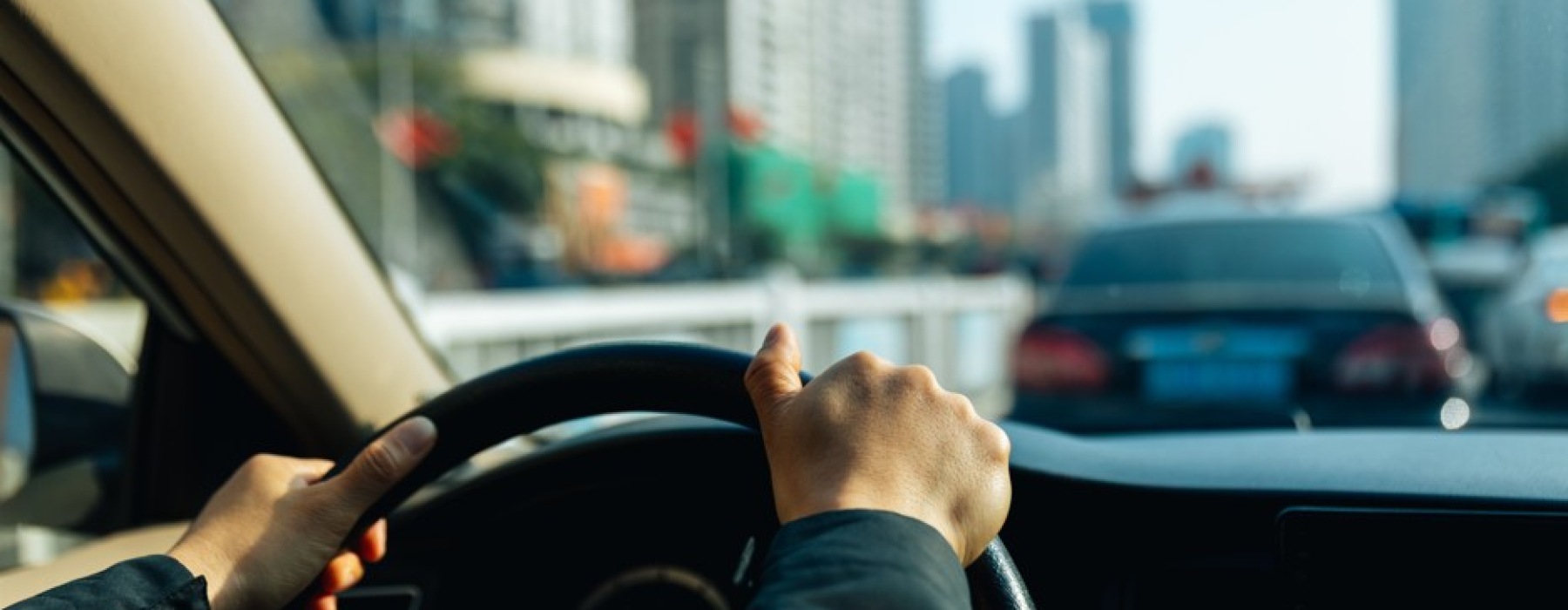 First-person perspective of a person driving a car through a busy Dallas-Fort Worth urban area with high-rise buildings in the background.