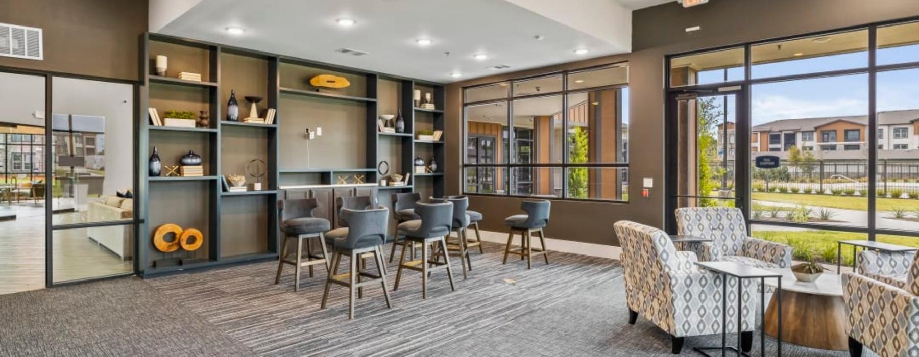 a room with a table chairs and shelves and large windows