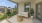 a white couch and a table on a patio with plants and a fence